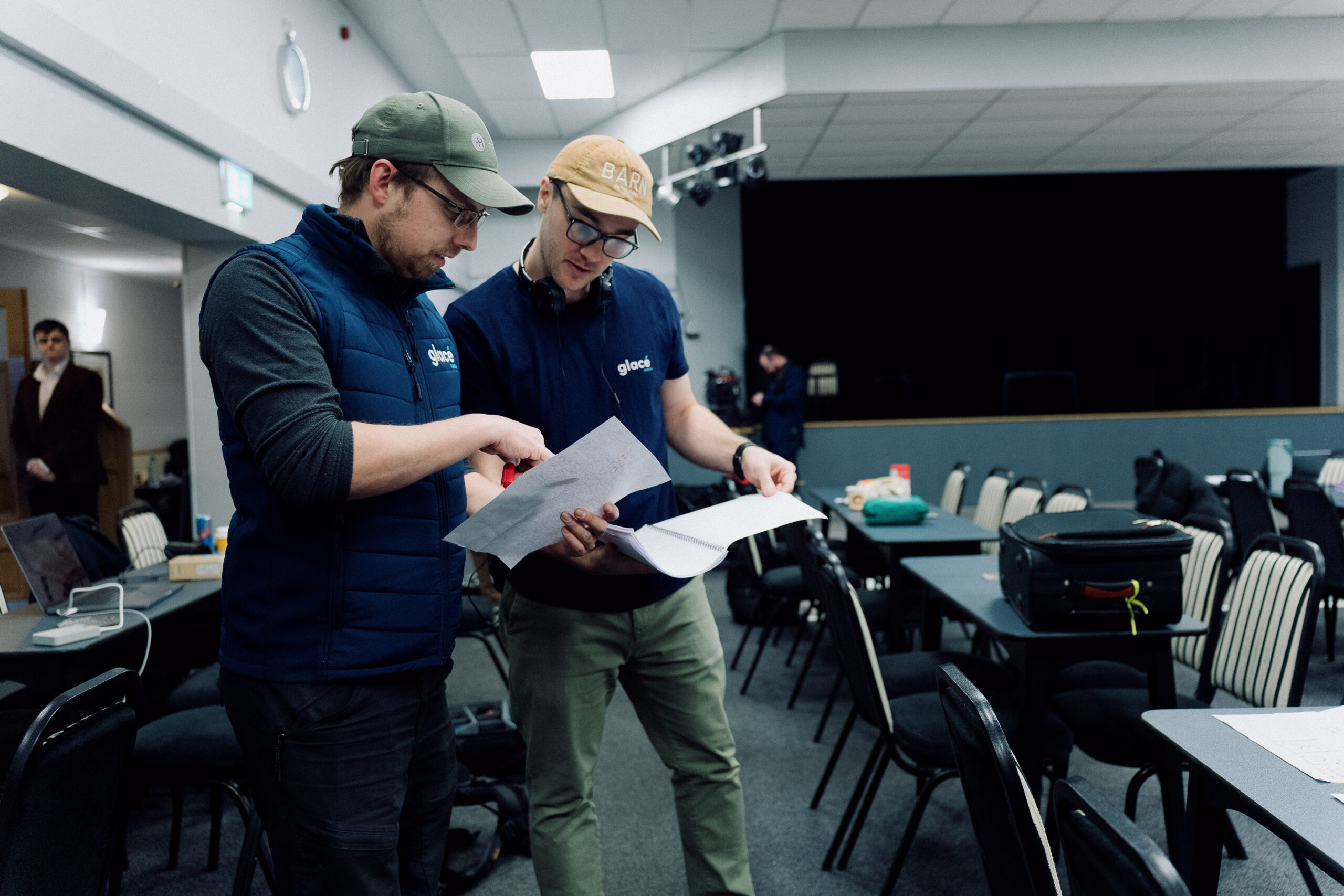 Two crew members from the film and video production company Glacé Media on the set of a film, looking at the a script.